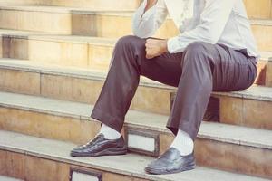 Close up of alone business man sitting and thinking outside office blurry city background photo