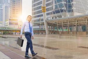 Young business man walking with his black carrying a briefcase city background, Start and Forward Concept. photo