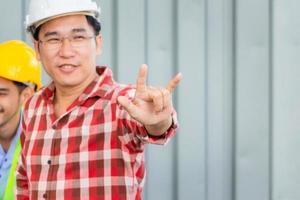 Cheerful engineer man in hard hat showing hand in I love you sign photo