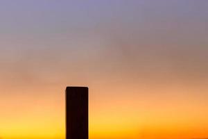 Silhouette of single wood square pole in sunset sky with copy space. photo