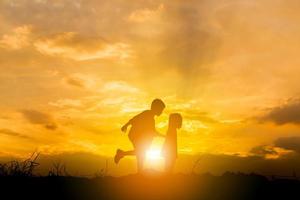 silueta de niño y niña jugando al fondo del atardecer, concepto de niños felices. foto