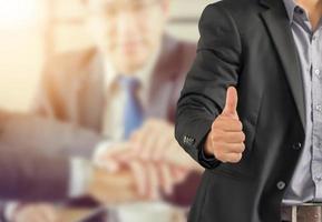Businessman giving thumb up as sign of Success over blurred business people team background photo