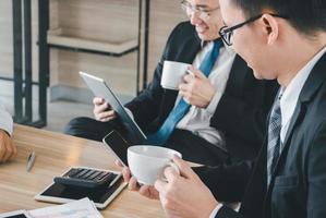 Group of Business Team Meeting Strategy Marketing in a coffee shop chatting to each other while using smartphone tablet laptop internet of things photo