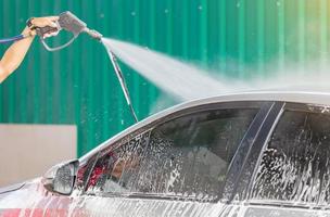 Car wash cleaning with soap and high pressure water washing, maintenance concept. photo