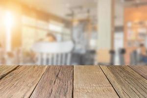 Perspectiva de mesa de madera vacía con fondo de cafetería borroso, utilizada para montar o exhibir sus productos. foto