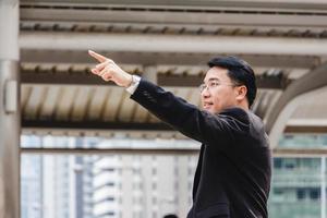 Portrait of businessman standing outside office and pointing to the sky photo