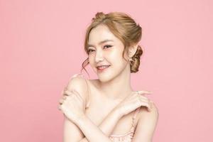 Beautiful young Asian woman have glitter on face wearing braces is feeling happy with clean fresh skin on pink background. Plastic surgery, Anti ageing, Cosmetology, beauty and spa, Female portrait. photo