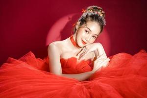 Young Asian pretty woman model in a posh stylish luxury red dress on a red background isolated. photo