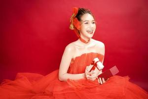 Young Asian pretty woman model in a posh stylish luxury red dress on a red background isolated. photo