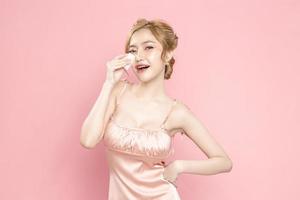 Beautiful young Asian woman holding cotton pads on face is feeling happy with clean fresh skin on pink background. Plastic surgery, Anti ageing, Cosmetology, beauty and spa, Female portrait. photo