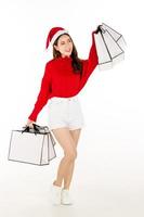 A cute Asian woman wearing a red dress with a Santa hat is holding a gift box. shopping concept. photo