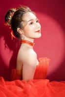 Young Asian pretty woman model in a posh stylish luxury red dress on a red background isolated. photo