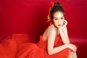 Young Asian pretty woman model in a posh stylish luxury red dress on a red background isolated. photo