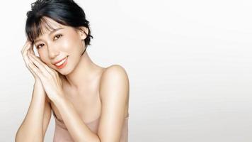 mujer joven feliz con una cara hermosa con una piel limpia y fresca perfecta sobre un fondo blanco. foto