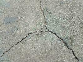 daños o grietas en el asfalto negro con malas hierbas foto