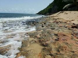 rocks, sand, and waves on beach in Puerto Rico photo