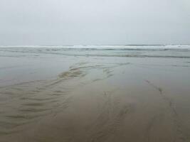 playa con arena mojada, océano y olas foto
