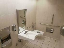 bathroom toilet with paper and metal railings and sink photo