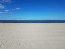 tire tracks and foot prints on combed beach and sea water photo