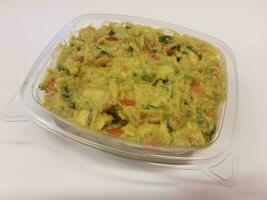 plastic container with avocado or guacamole on white surface photo