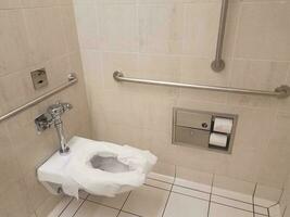 bathroom toilet with paper and metal railings photo