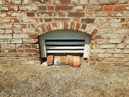 basement window with red bricks and brown grass photo