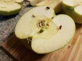 manzana en tabla de cortar de madera creciendo un brote foto