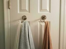 towels hanging on hooks on white bathroom door photo