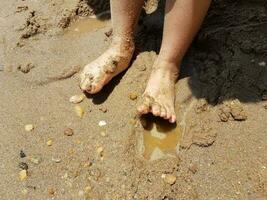 child's feet in the sand with rocks photo