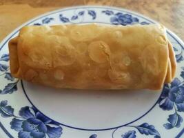 rollo de huevo chino en un plato blanco en la mesa foto