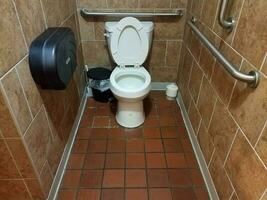 bathroom stall with toilet and tiled floors photo
