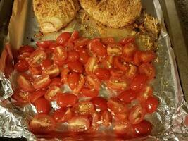 baking tray with sliced red tomatoes and chicken photo