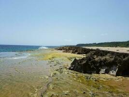 rocas, arena y olas en la playa de puerto rico foto