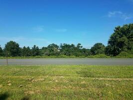 road and mowed grass with metal posts and rope fence on the side of the road photo