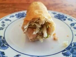 Chinese egg roll on white plate on table with shrimp and cabbage photo