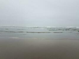 playa con arena mojada, océano y olas foto