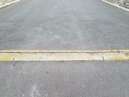 elevated asphalt or pavement path with yellow curb or ramp photo