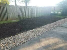 asphalt driveway with stones and dirt and wood fence photo