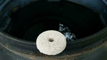 circular white mosquito tablet insecticide on edge of rain barrel photo