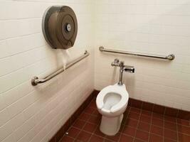 toilet and red square floor tiles in bathroom or restroom photo