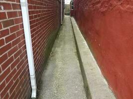 narrow alley with red wall and bricks on masonry photo