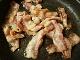 bacon strips cooking in frying pan or skillet photo