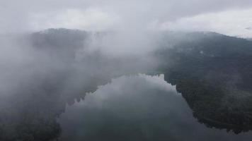 Aerial fly away low cloud of lake at tropical rainforest