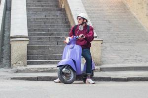 Varón joven elegante con colorido motor scooter foto