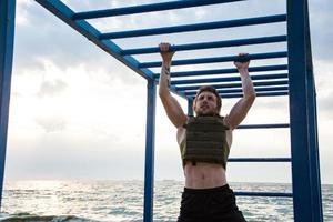 joven atleta barbudo entrenando al aire libre con chaleco ponderado, ejercicio con portador de placa militar foto