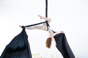mujer colgada en seda aérea en estudio blanco foto