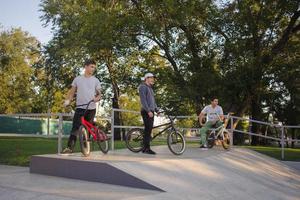 grupo de jóvenes con bicicletas bmx en skate plaza, ciclistas acrobáticos en skatepark foto