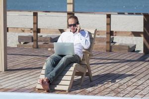 young men with laptopp working near the pool, freelancer in hotel on vacation with notebook photo