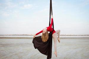 exercises with aerial silk outdoor, sky background. beautiful fit woman training acrobatic in airt. photo