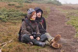 pareja joven excursionistas con tazas termos en el bosque, viajeros en mauntains bebiendo té o café foto